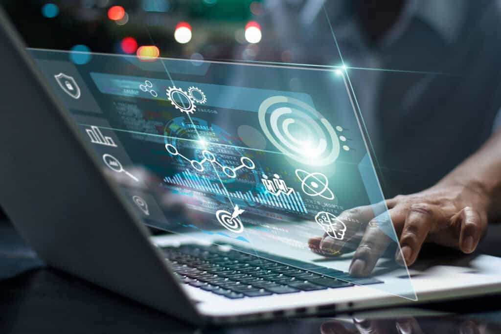 Business technology concept showing a person using a laptop with digital data visualization, AI analytics, and futuristic interface.