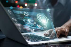 Business technology concept showing a person using a laptop with digital data visualization, AI analytics, and futuristic interface.