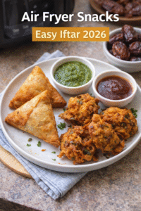 Air fryer iftar platter with crispy chicken samosas and pakoras served with green chutney, tamarind chutney, and dates on a kitchen counter, natural light, Ramadan snack setup.